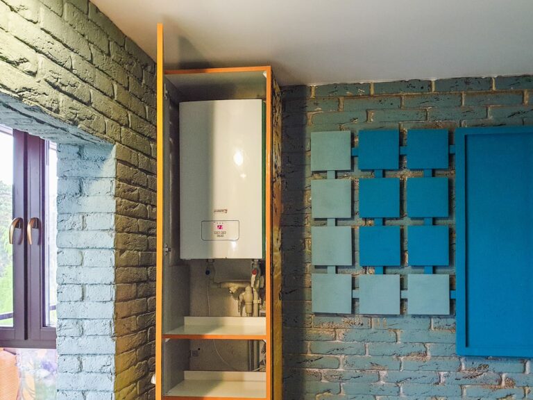 Wall-mounted combi boiler inside a home cupboard, the boiler checked during an annual service
