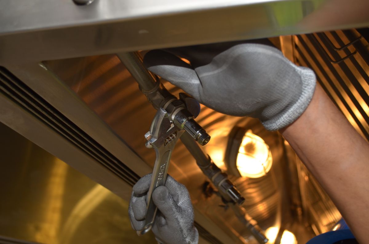 A plumber using an adjustable wrench to repair a pipe fitting after a burst