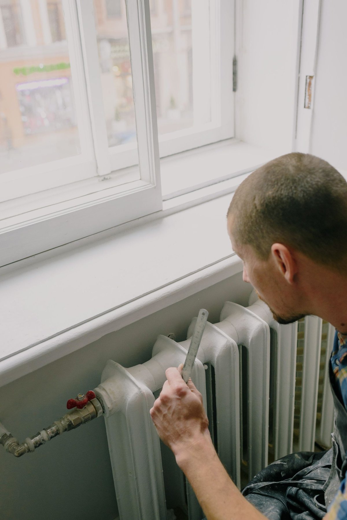 Engineer checking a radiator and its valve as part of a heating system service in a Bradford home