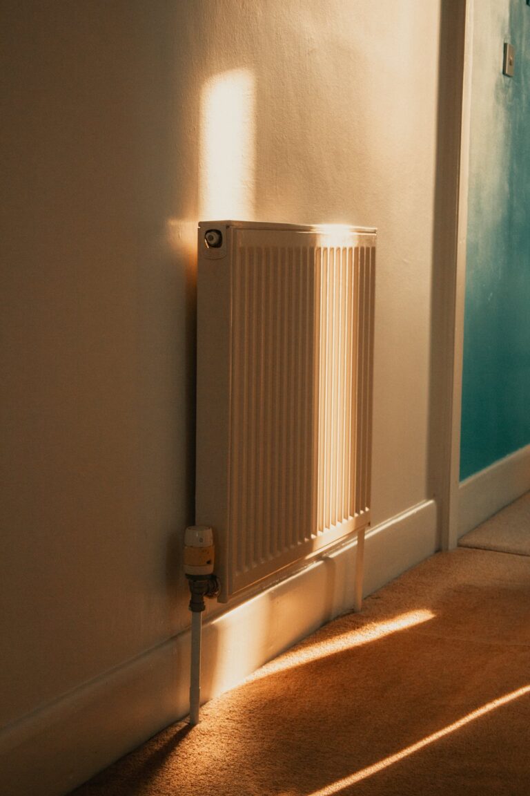 White panel radiator with a thermostatic valve in a sunlit home hallway