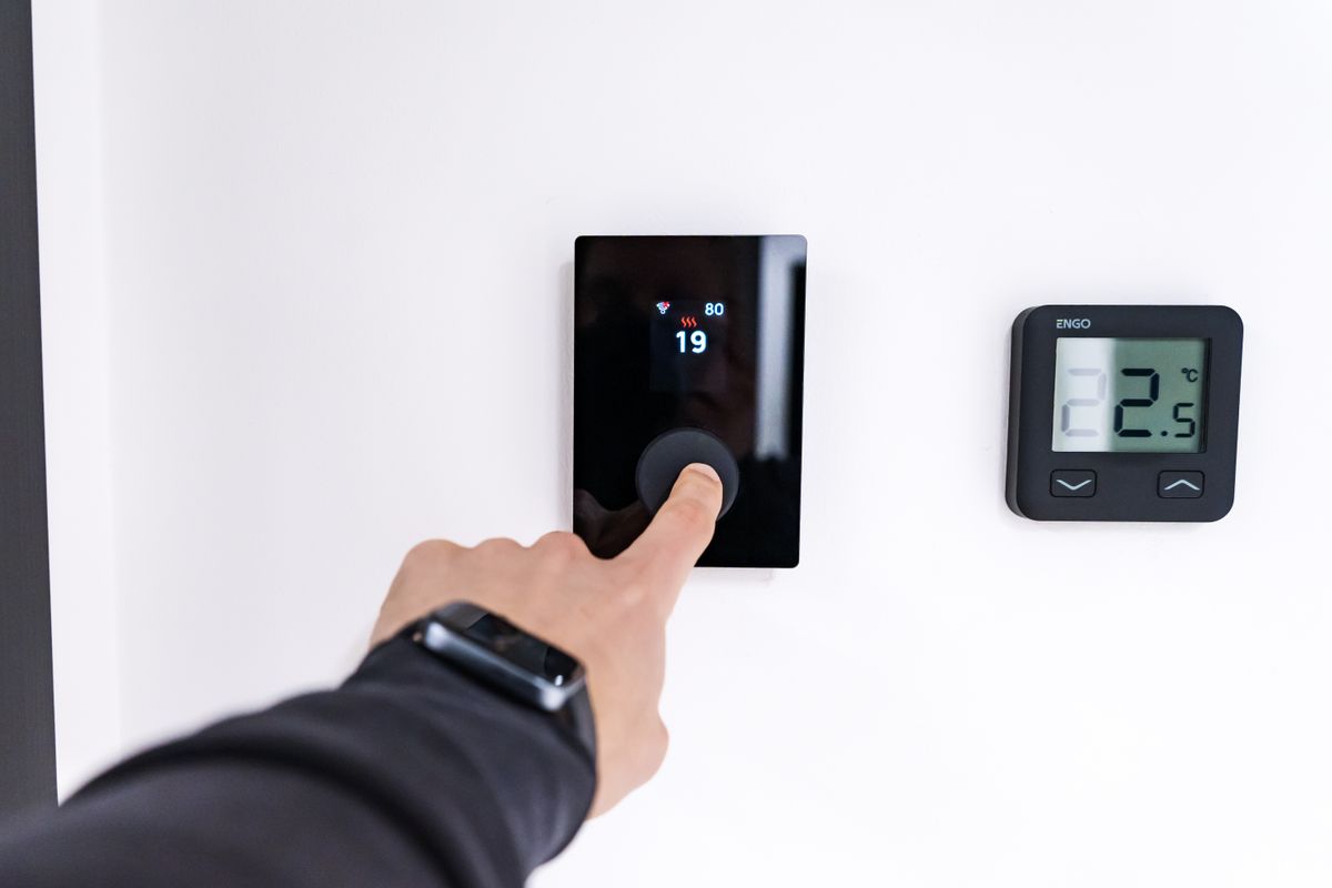 Hand turning up a room thermostat while checking why the heating has not come on